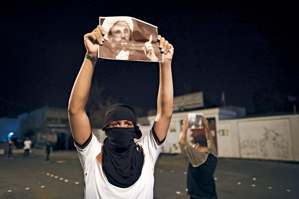 Bahraini protestors hold up portraits of Saudi Shiite Cleric Nimr Al Nimr during clashes with riot police following a protest in solidarity with Al Nimr, in the village of Sanabis, west of Manama, on October 15, 2014. A Saudi court sentenced prominent Shiite cleric Nimr Al-Nimr to death after convicting the anti-government protest leader of  "sedition", his brother and lawyer said. AFP PHOTO/MOHAMMED AL-SHAIKH